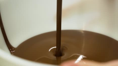 Chocolate-flowing-into-bowl,-preparation-of-milk-chocolate-at-cake-factory,-Slow-Motion