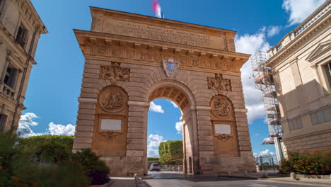 Traffic-moves-through-Porte-du-Peyrou-monument,-Montpellier,-France
