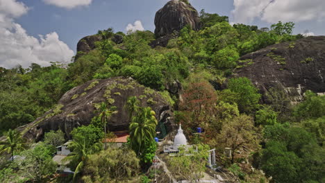 Algama-Len-Viharaya-Sri-Lanka-Luftaufnahme-V4-Niedriger-überflug-Alter-Buddhistischer-Tempel-Hoch-Oben-Auf-Dem-Hügel-In-Richtung-Des-Felsigen-Berggipfels,-Der-Die-Dschungelbuschumgebung-Einfängt-–-Aufgenommen-Mit-Mavic-3-Cine-–-April-2023