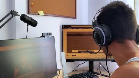 Boy-Enjoying-Online-Videos-with-Earphones-on-Computer---View-from-Behind-in-Bedroom