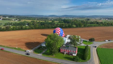 Aerial-top-down-of-american-countryside-with-driving-cars-on-road-and-american-hot-air-balloon-landing