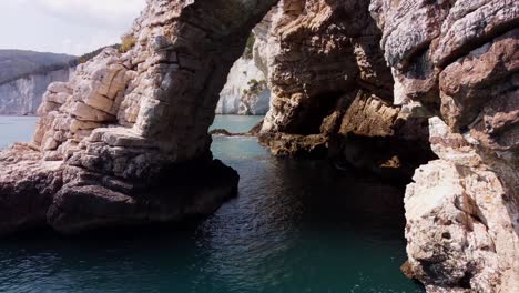 Flying-drone-through-a-stone-cliff-arch-at-the-mediteran-sea-in-italy