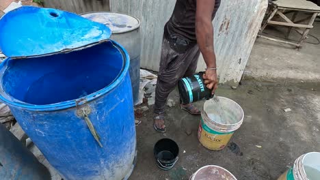 Due-to-water-shortage,-a-person-is-pouring-enough-water-in-a-bucket