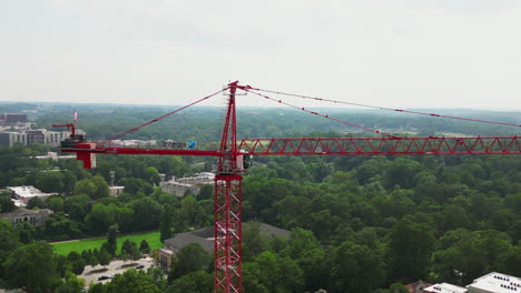 Pull-back-shot-of-tall-red-tower-crane-on-construction-site-in-city
