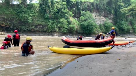 Canoes-are-docked-along-the-riverbank,-with-people-gathered-by-the-riverside