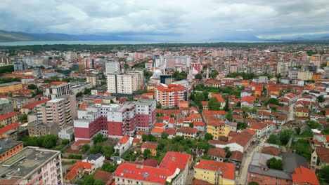 Aerial-drone-pan-shot-from-left-to-right-over-city-buildings-in-Shkodra,-also-known-as-Shkoder-or-Scutari-in-northwestern-Albania