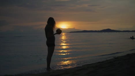 Women-at-a-beach-vacation-drinking-fresh-coconut-water-at-sunset