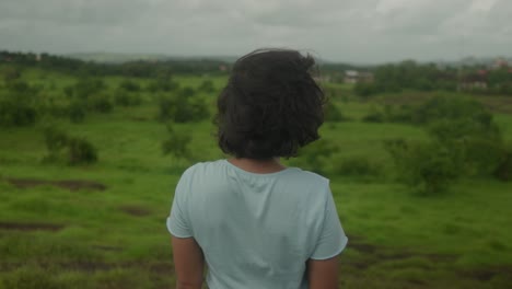 Indian-young-girl-stands-at-the-edge-of-the-lush-Goa-India-forest,-her-gaze-fixed-upon-the-enchanting-greenery-ahead