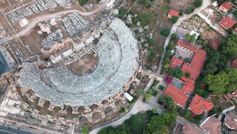 Vista-Aérea-Mirando-Hacia-Abajo-Sobre-El-Histórico-Anfiteatro-Lateral,-Turquía-Y-Los-Tradicionales-Tejados-Residenciales-Del-Casco-Antiguo.