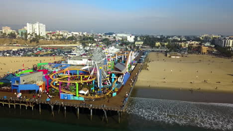 Aerial-view-passing-the-Santa-Monica-pier,-golden-hour-in-sunny-Los-Angeles,-USA