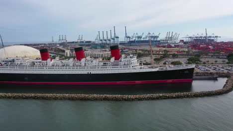 Aerial-view-around-the-Queen-mary-ship-docked,-cloudy-day-in-Los-Angeles,-USA