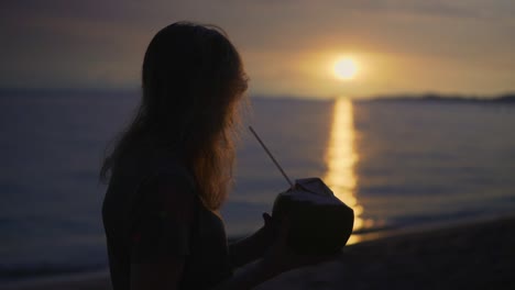 Frauen-Genießen-Eine-Frische-Kokosnuss-An-Einem-Wunderschönen-Strand-Bei-Sonnenuntergang