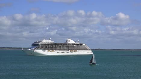 Cruise-liner-with-small-yacht-sailing-by-and-tender-returning-to-the-liner-Dunmore-East-Waterford-Ireland