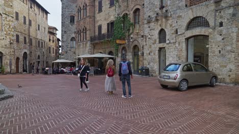 Blick-Auf-Den-Platz-Mit-Menschen-Und-Alten-Gebäuden-In-San-Gimignano,-Italien
