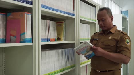 El-Profesor-Toma-Un-Libro-De-La-Estantería-De-La-Biblioteca