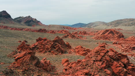 Aerial-view-low-over-piles-of-red-rock-in-the-deserts-of-sunny-Nevada,-USA