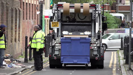 Refuse-workers-throw-bags-of-rubbish-into-the-back-of-a-refuse-truck-s-on-Brick-Lane-following-two-weeks-of-refuse-strikes-in-Tower-Hamlets-Borough
