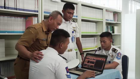 Segelberufsschüler-Oder-Taruna-Arbeiten-Gemeinsam-An-Einem-Studienprojekt-Im-Bibliotheksraum,-Mit-Büchern,-Laptops,-Und-Diskutieren-über-Forschungsergebnisse