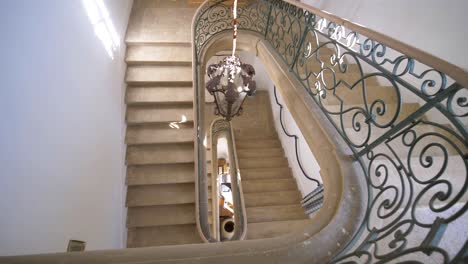 Slow-revealing-shot-of-a-luxury-stone-staircase-with-intricate-metal-railings