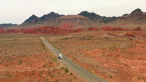 Aerial-view-backwards-in-front-of-a-RV-truck-driving-on-a-road-in-the-deserts-of-USA