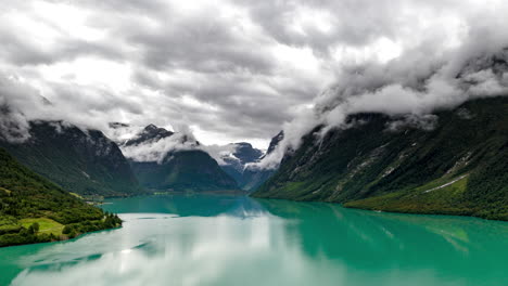 Dramatic-drone-hyperlapse-of-mountain-fog-twirling-around-Loen-Mountains,-Norway-Lovatnet-Loen-Lake