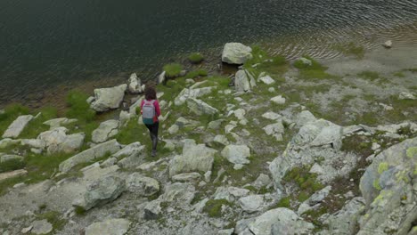 Vista-Superior-De-Una-Mujer-Caminando-Por-Senderos-Rocosos-Cerca-De-La-Orilla-Del-Río-En-Campagneda,-Valmalenco,-Italia