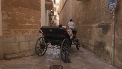 Horse-drawn-carriages-tour-with-tourists-cruising-in-the-narrow-streets-of-Palma-de-Majorca-in-Spain