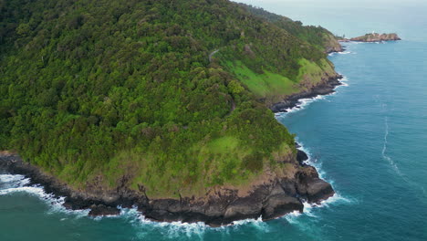 Fly-around-rocky-coast-and-dense-green-vegetation-on-tropical-island