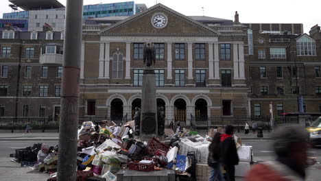 Menschen-Gehen-An-Einem-Riesigen-Müllhaufen-Vorbei,-Der-Um-Eine-Statue-Vor-Dem-Rathaus-Von-Tower-Hamlets-Aufgetürmt-Ist,-Während-Ein-Müllwagen-Nach-Zweiwöchigen-Müllstreiks-Im-Bezirk-Vorbeifährt