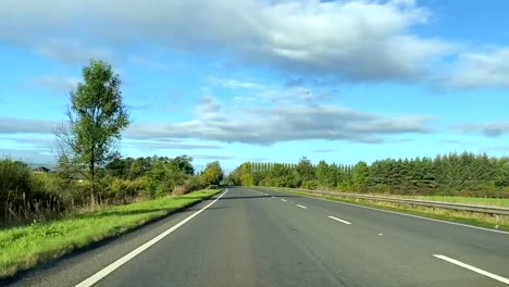 Scenery-from-the-car-window-driving-on-a-tree-filled-road-in-Scotland