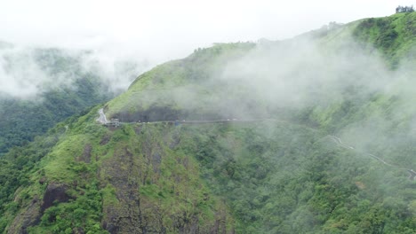 Hermosa-Vista-Del-Paisaje-En-Vagamon-Idukki-Kerala,-Vista-Aérea-De-La-Carretera-En-Un-Hermoso-Bosque-Verde-Y-Nubes-Bajas,-Hermosa-Vista-De-Nubes-Rápidas-Que-Se-Desplazan-Sobre-Montañas-Y-Colinas