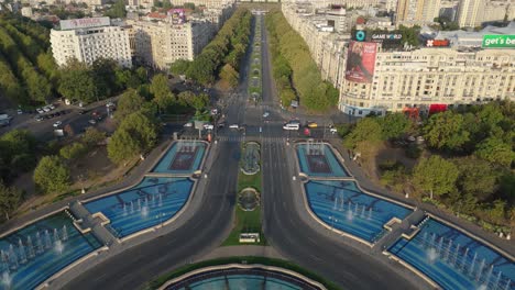 Vista-Aérea-De-Las-Fuentes-Artesianas-De-La-Plaza-Unirii,-Con-El-Palacio-Del-Parlamento-Al-Fondo,-Bucarest,-Rumania