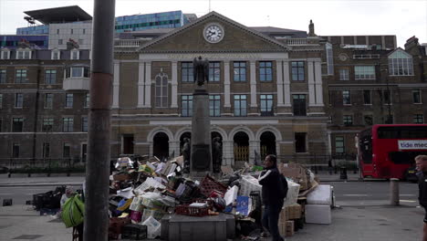 En-Cámara-Lenta,-La-Gente-Pasa-Junto-A-Un-Enorme-Montículo-De-Basura-Apilada-Alrededor-De-Una-Estatua-Frente-Al-Ayuntamiento-De-Tower-Hamlets-Después-De-Dos-Semanas-De-Huelgas-De-Basura-En-El-Municipio.