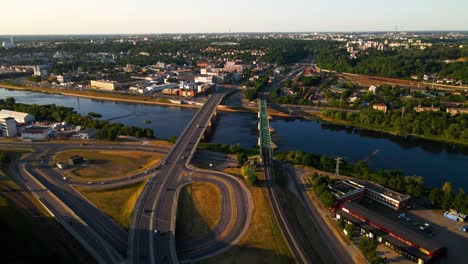 Aerial-shot-of-the-traffic-on-the-road-and-bridge-through-Nemunas-river-in-Kaunas,-Lithuania