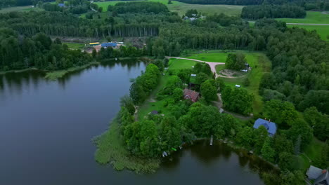 High-drone-flight-along-the-shores-of-a-lake-with-beautiful-houses-and-green-meadows