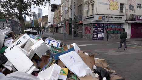 In-slow-motion-a-man-walks-past-a-giant-mound-of-rubbish-on-the-Whitechapel-Road-following-two-weeks-of-refuse-strikes-in-Tower-Hamlets-Borough