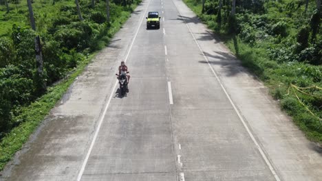 Group-of-Tourists-people-and-backpackers-riding-Motorcycles-on-palm-tree-road-waving-to-camera-on-Siargao-island