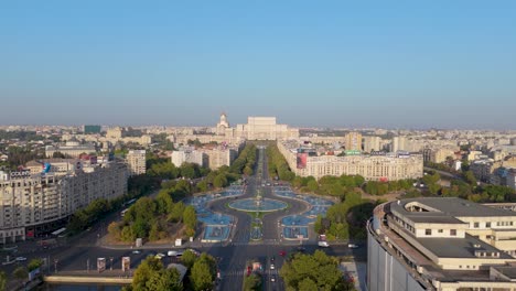 Vista-De-Drones-De-Las-Fuentes-Artesianas-De-La-Plaza-Unirii,-Con-El-Palacio-Del-Parlamento-Al-Fondo,-Bucarest,-Rumania