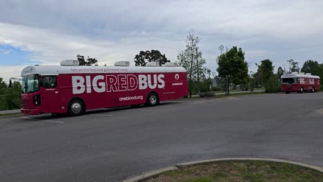 Onebloods-Große-Rote-Bus-Blutspendefahrzeuge-Stehen-Auf-Dem-Parkplatz-Hinter-Der-Einrichtung