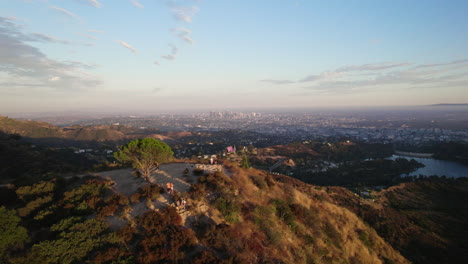 Eine-Filmische-Luftaufnahme-Von-Los-Angeles-Zur-Goldenen-Stunde,-Vorbei-Am-Weisheitsbaum-Und-Dem-Hollywood-Stausee