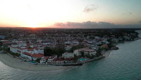 Drone-footage-of-Waterfront-Stone-Town,-Zanzibar,-Tanzania-at-sunrise