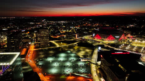 Toma-Aérea-De-Un-Dron-Que-Muestra-El-Tráfico-En-La-Carretera-Y-La-Iluminación-Del-Estadio-Mercedes-Benz-En-Atlanta-Después-Del-Atardecer-En-El-Horizonte.