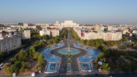 Vista-Aérea-De-Las-Fuentes-Artesianas-De-La-Plaza-Unirii,-Con-El-Palacio-Del-Parlamento-Al-Fondo,-Bucarest,-Rumania