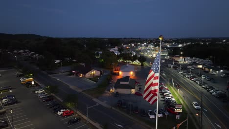American-flag-waving-above-small-town-in-USA-at-night