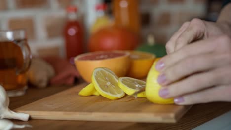Hands-of-unrecognizable-woman-cutting-lemon-for-winter-tea.
