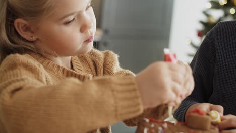 Video-of-little-girl-focused-on-decorating-gingerbread-house