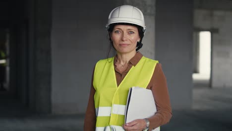 Portrait-of-female-caucasian-engineer-holding-document-while-standing-on-construction-site.