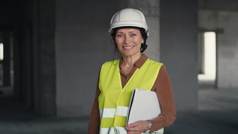Portrait-of-female-caucasian-engineer-holding-document-while-standing-on-construction-site.