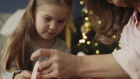 Tracking-video-of-grandma-with-granddaughter-packing-together-Christmas-present