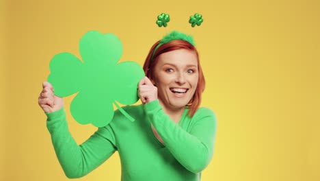 Playful-woman-holding-clover-shaped-banner-with-copy-space